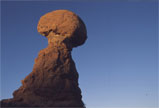 A rounded sandstone formation against blue sky