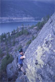 A climber on a rock face above a lake