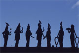 A row of statues silhouetted against blue sky